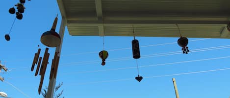 A clear blue sky with various hanging objects, including a wind chime, a decorative hanging ornament, and a hanging light fixture.