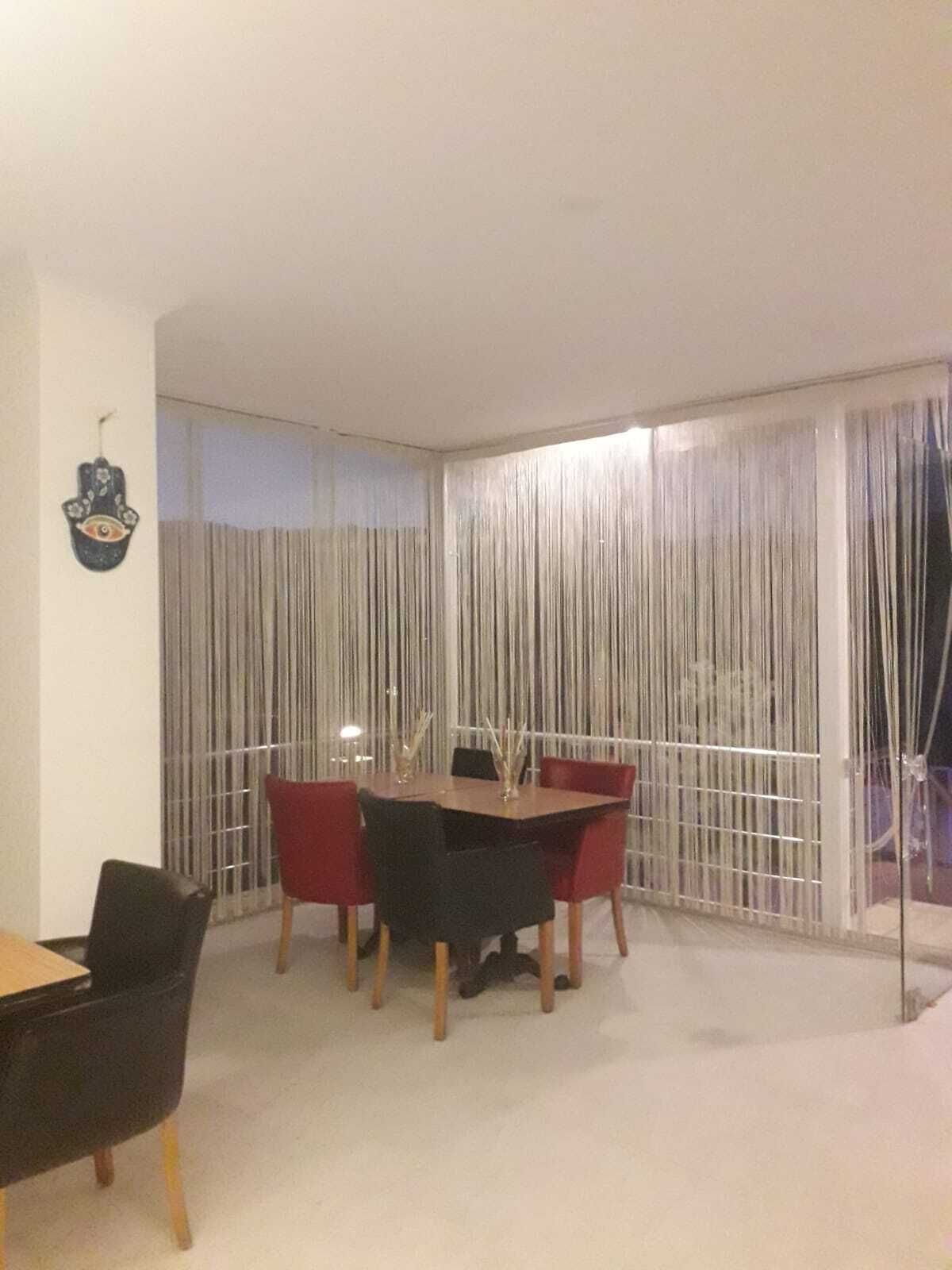 Ein Essbereich mit Tisch und Stühlen, einer Wanddekoration und Blick durch ein fensterbedecktes Vorhang.
