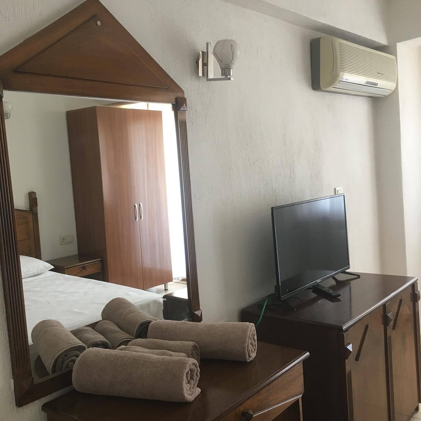 A hotel room with a wooden canopy bed, a flat-screen TV, a wooden dresser, and a mirror.