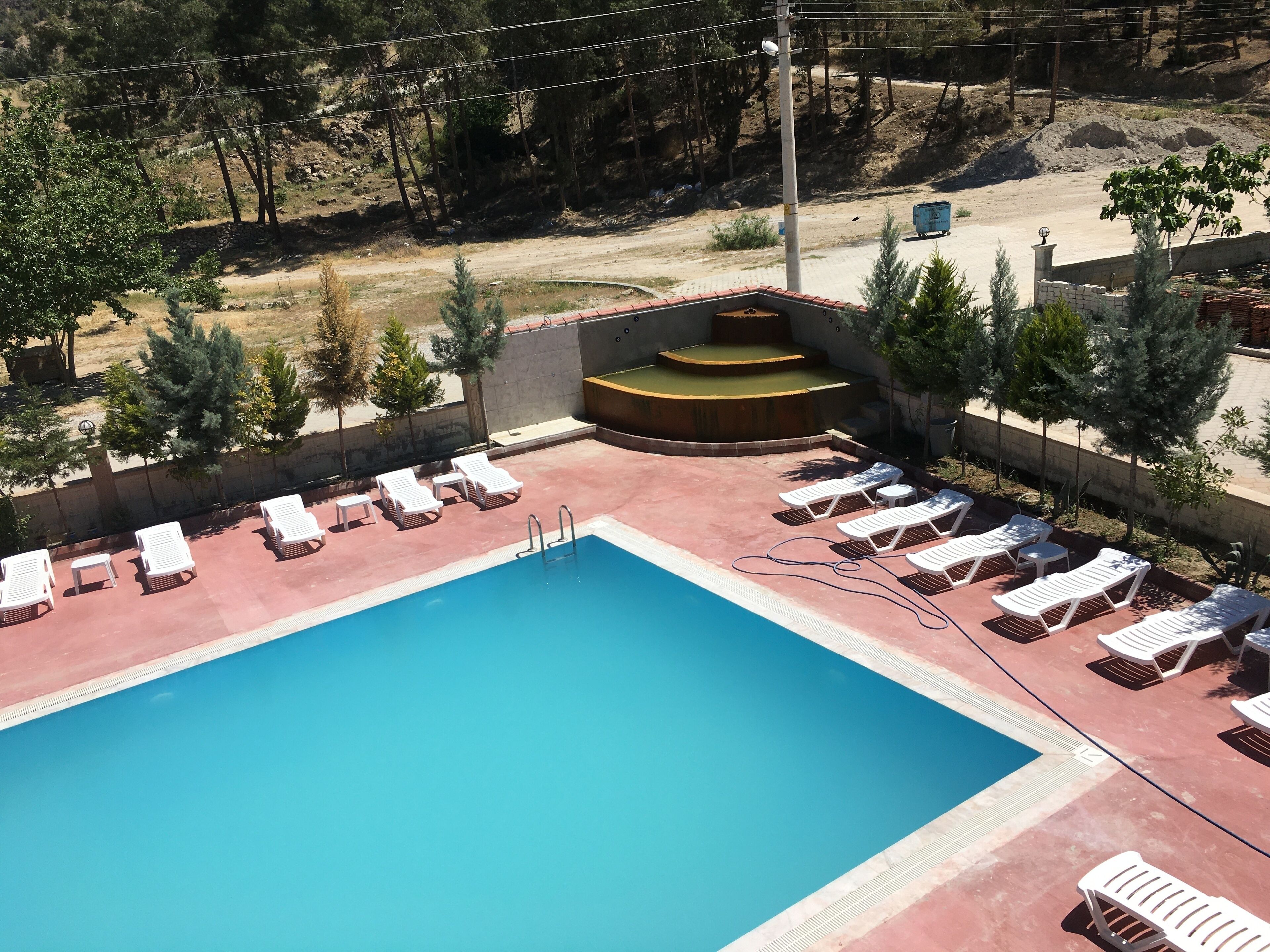 A swimming pool with white lounge chairs and a stage area.