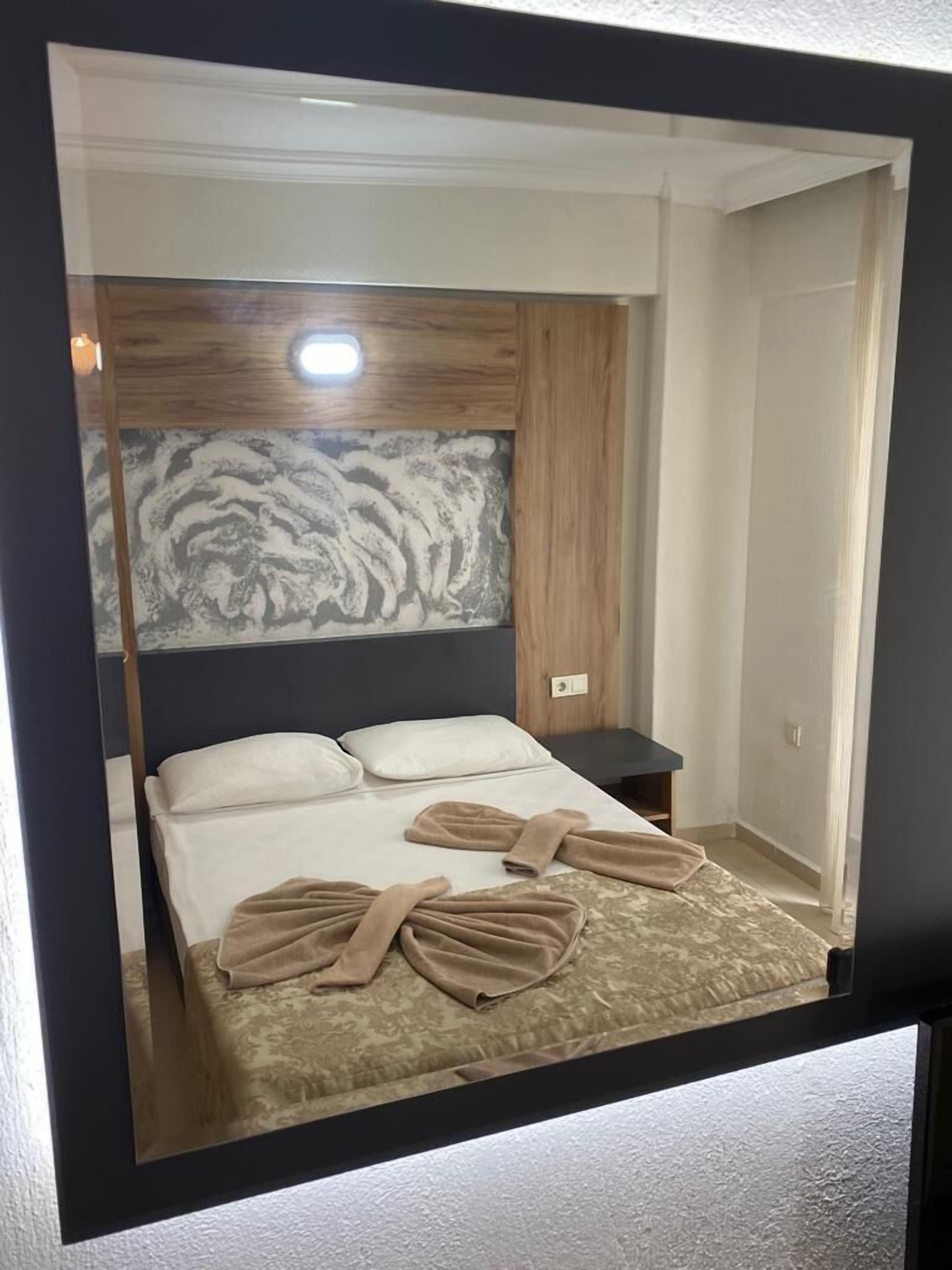 A neatly made bed with a headboard, a bedside table, and a wall with a textured pattern.