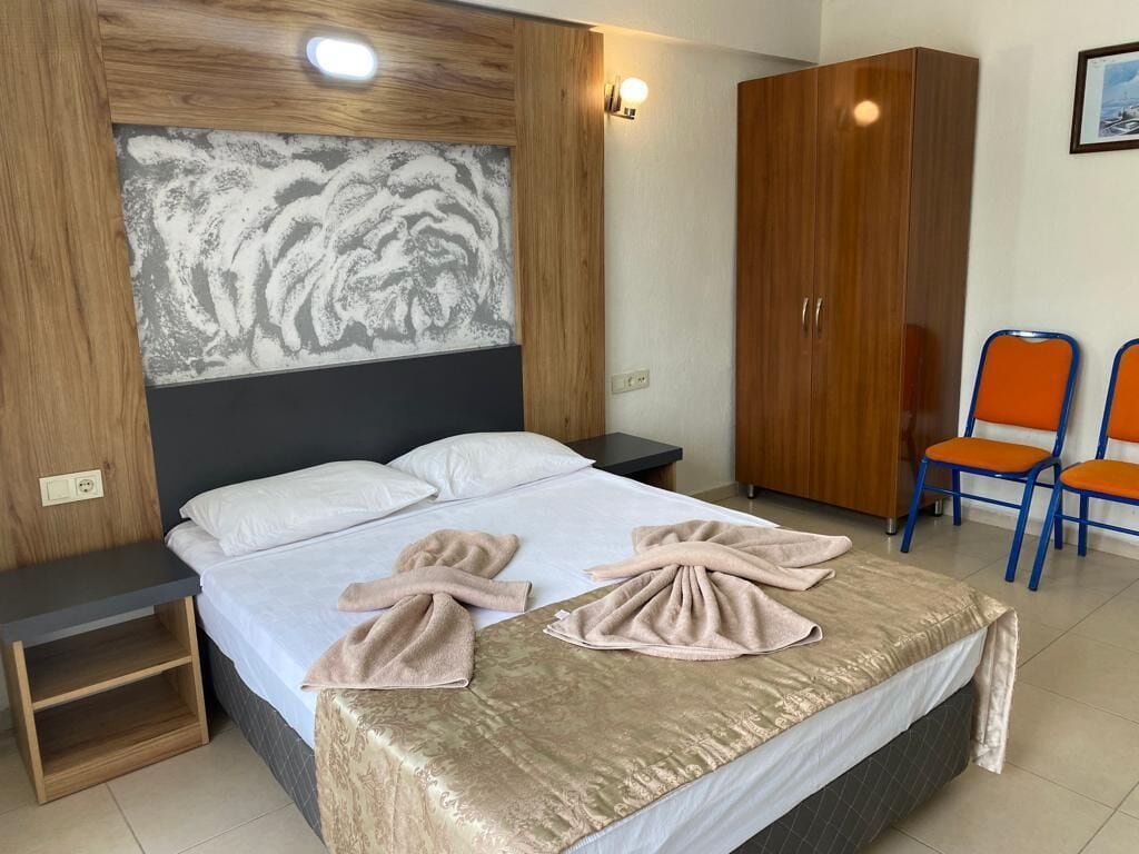 Ein Schlafzimmer mit einem Bett, zwei Nachttischen, einem Kleiderschrank und zwei Stühlen.
