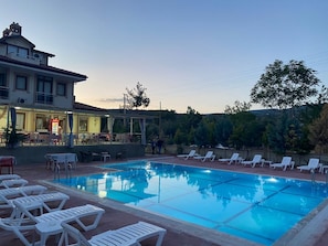 A swimming pool with lounge chairs, a restaurant with outdoor seating, and a building with a balcony. - Mucize Termal Spa (Denizli)