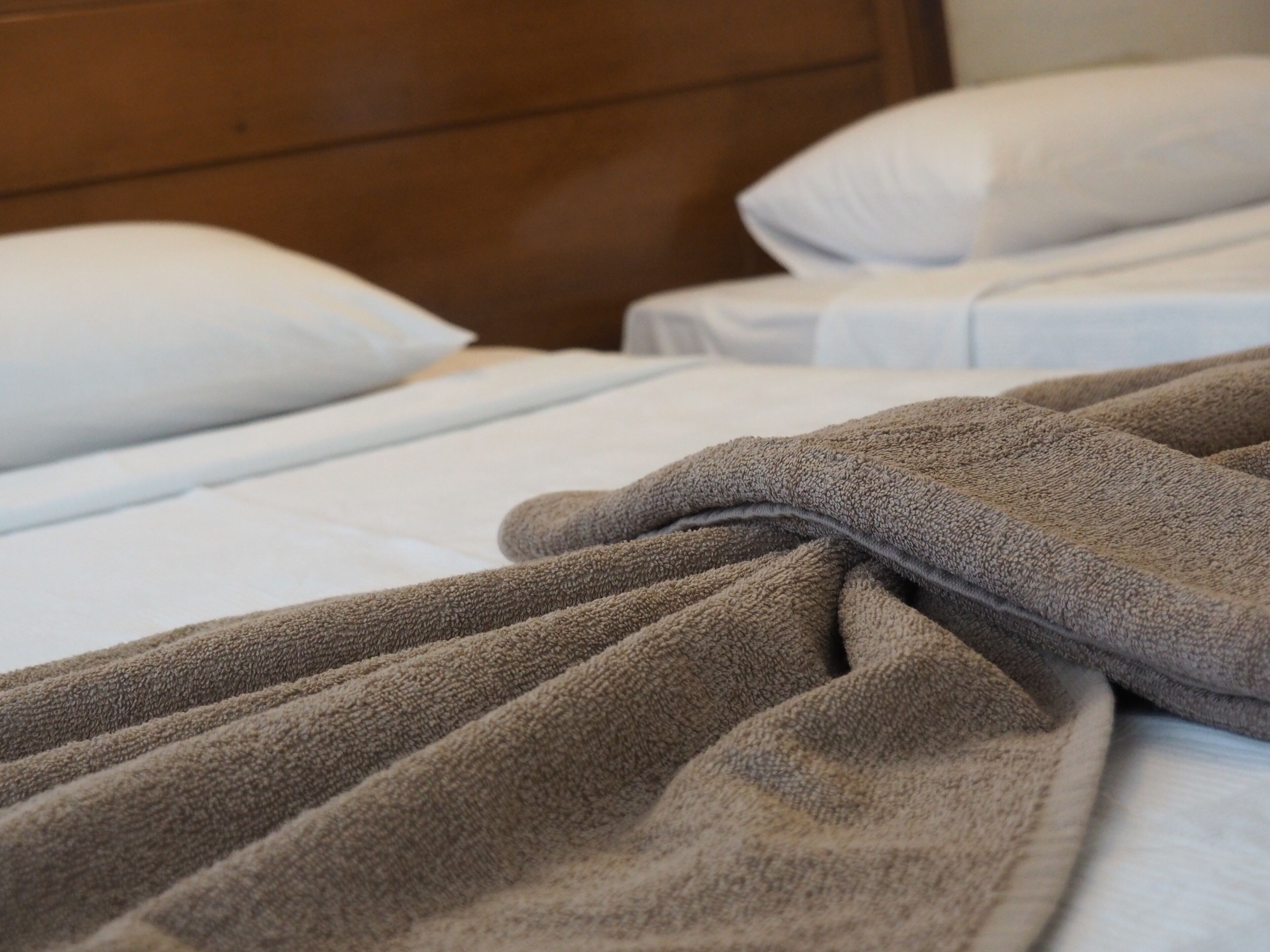 Una cama con una manta marrón y sábanas blancas.