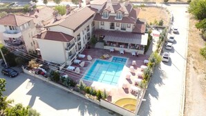 Un hotel de varios pisos con piscina, mobiliario exterior y zona de estacionamiento.