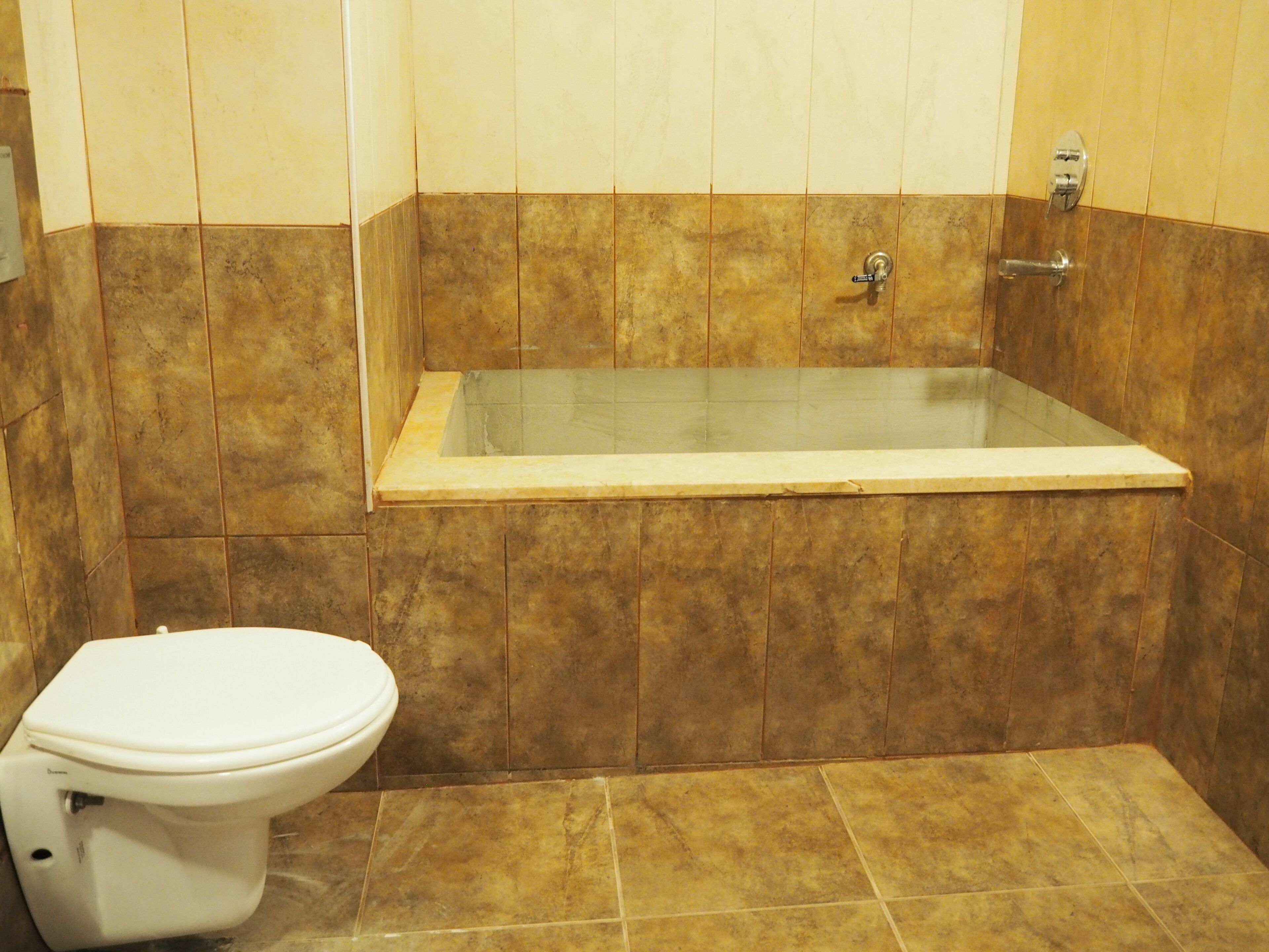 A bathroom with a bathtub, toilet, and tiled walls.