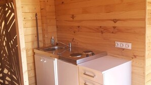 Una cocina compacta con paredes de madera, un lavamanos, una estufa y dos cubos de basura.