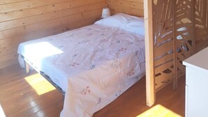 Una habitación de cabaña de madera con una cama, una mesita de noche y un panel decorativo.