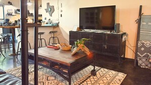 A modern living room with a large flat-screen TV, a dark wooden coffee table, and a patterned rug. - Casa Acero - hot tub spa, comfortable, views, private (Alpine)