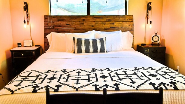 A bed with a patterned bedspread, a wooden headboard, and two bedside tables with lamps. - Casa Acero - hot tub spa, comfortable, views, private (Alpine)