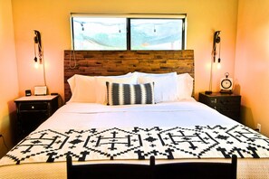 A bed with a patterned bedspread, a wooden headboard, and two bedside tables with lamps. - Casa Acero - hot tub spa, comfortable, views, private (Alpine)