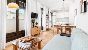 A modern living room with a sofa, coffee table, and dining area.