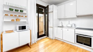 A modern kitchen with white cabinets, a microwave, a toaster, and a coffee maker.