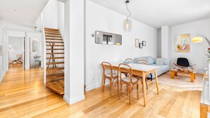 A modern living room with a wooden staircase, a dining area, and a sofa.