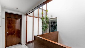 A modern interior with a wooden door, a wooden reception desk, and a large window with a view of a building.