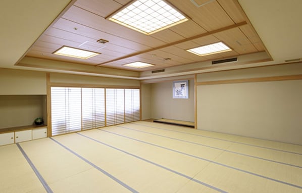 Een kamer met tatami matten, schuifdeuren, een tatami vloer en een plafond met inbouwspots.
