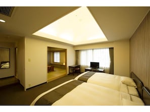Una habitación de hotel con cama, escritorio, televisor y tragaluz.