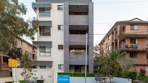 A modern multi-story building with a flat roof and a sign indicating it is for lease. - Cosy and Bright Studio Next to Westmead Hospital (Westmead)