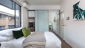 A modern bedroom with a large bed, a microwave, and a television in the background. - Cosy and Bright Studio Next to Westmead Hospital (Westmead)