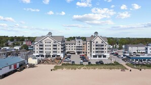 A large hotel with multiple floors and balconies, situated on a beachfront with a parking lot in front. - Grand Victorian unit 309, 3 bedrooms (Old Orchard Beach)