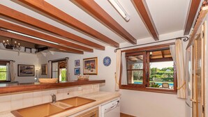 A kitchen with wooden beams, a sink, a dishwasher, and a window with a view of greenery. - 3 bedroom villa, with private pool and BBQ, Pollensa (Pollensa)
