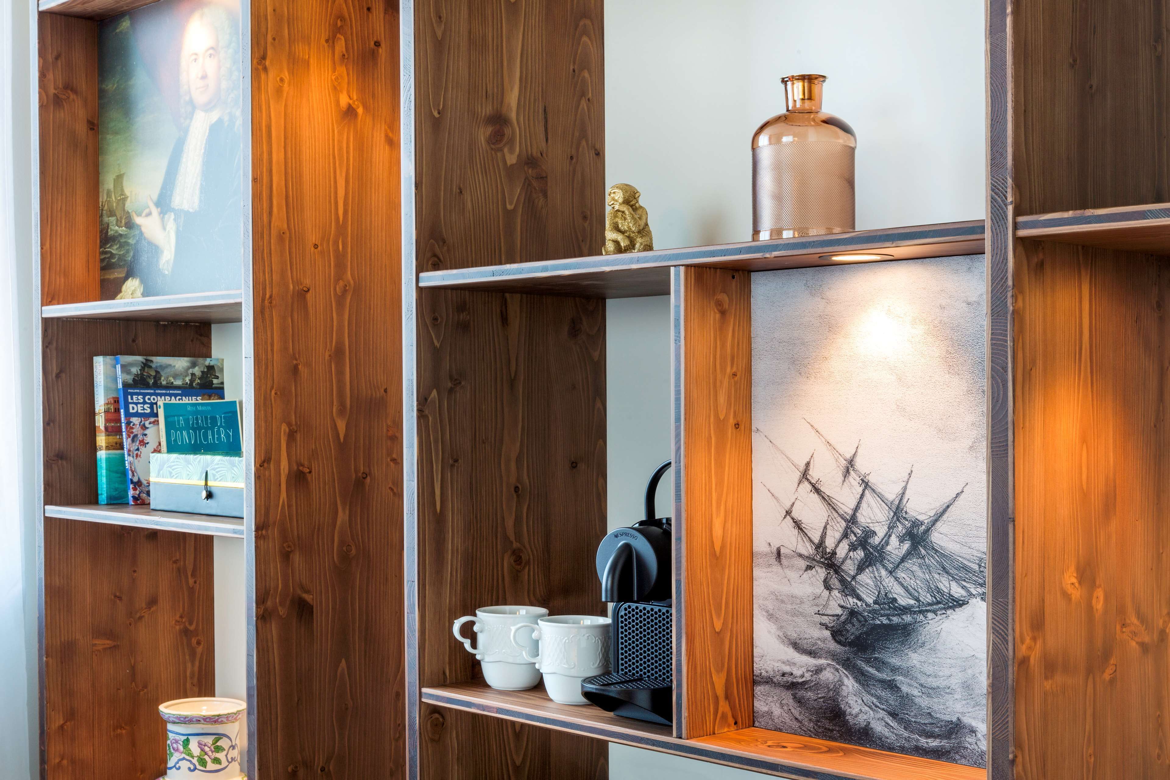Una estantería de madera con varios objetos, incluyendo libros, una cafetera y adornos.
