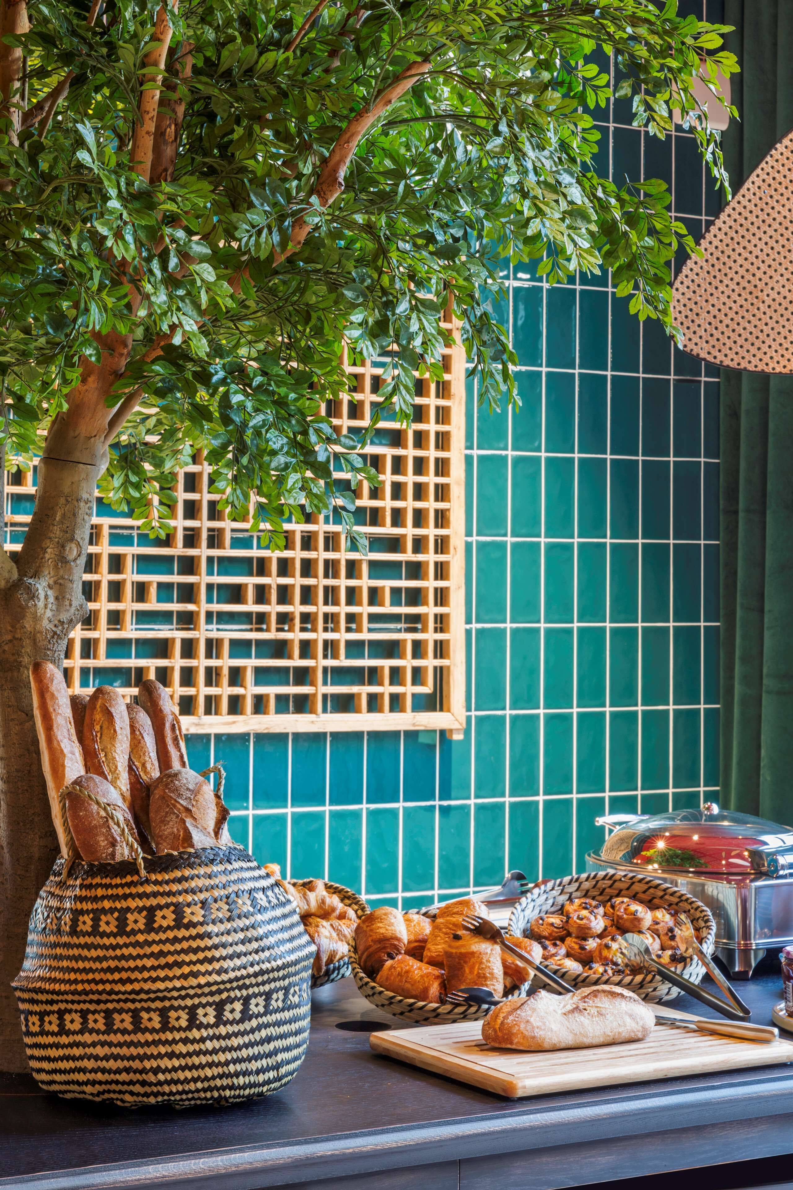 A table with bread and pastries, a patterned basket, and a window with a grid pattern.