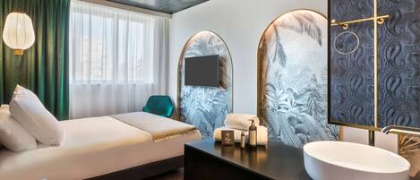 A modern hotel room with a bed, a vanity with a large mirror, and a window with curtains.
