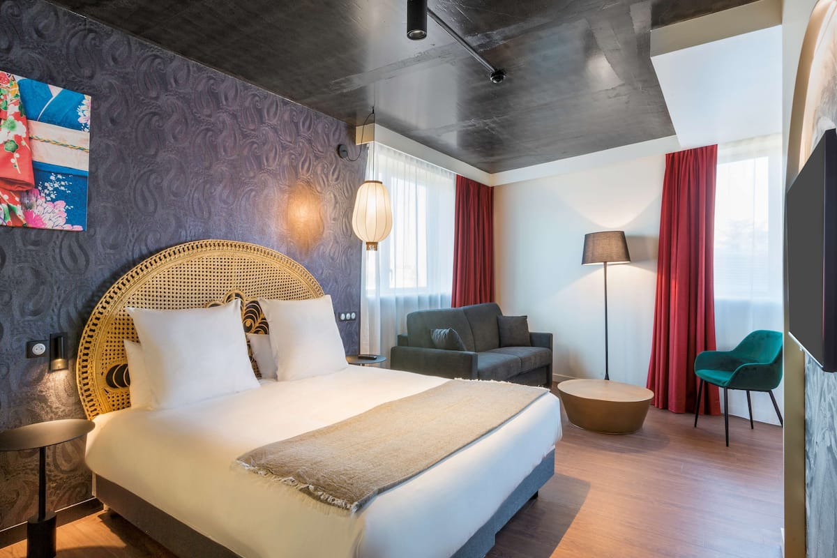 Een moderne hotelkamer met een groot bed, een sofa, een ronde salontafel en een televisie.