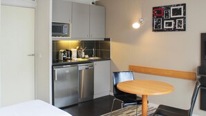 Une chambre d’hôtel compacte comprenant un coin cuisine, un lit, une table ronde et une chaise.