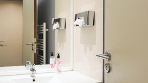 Une salle de bain avec un lavabo blanc, un miroir et un porte-serviettes.