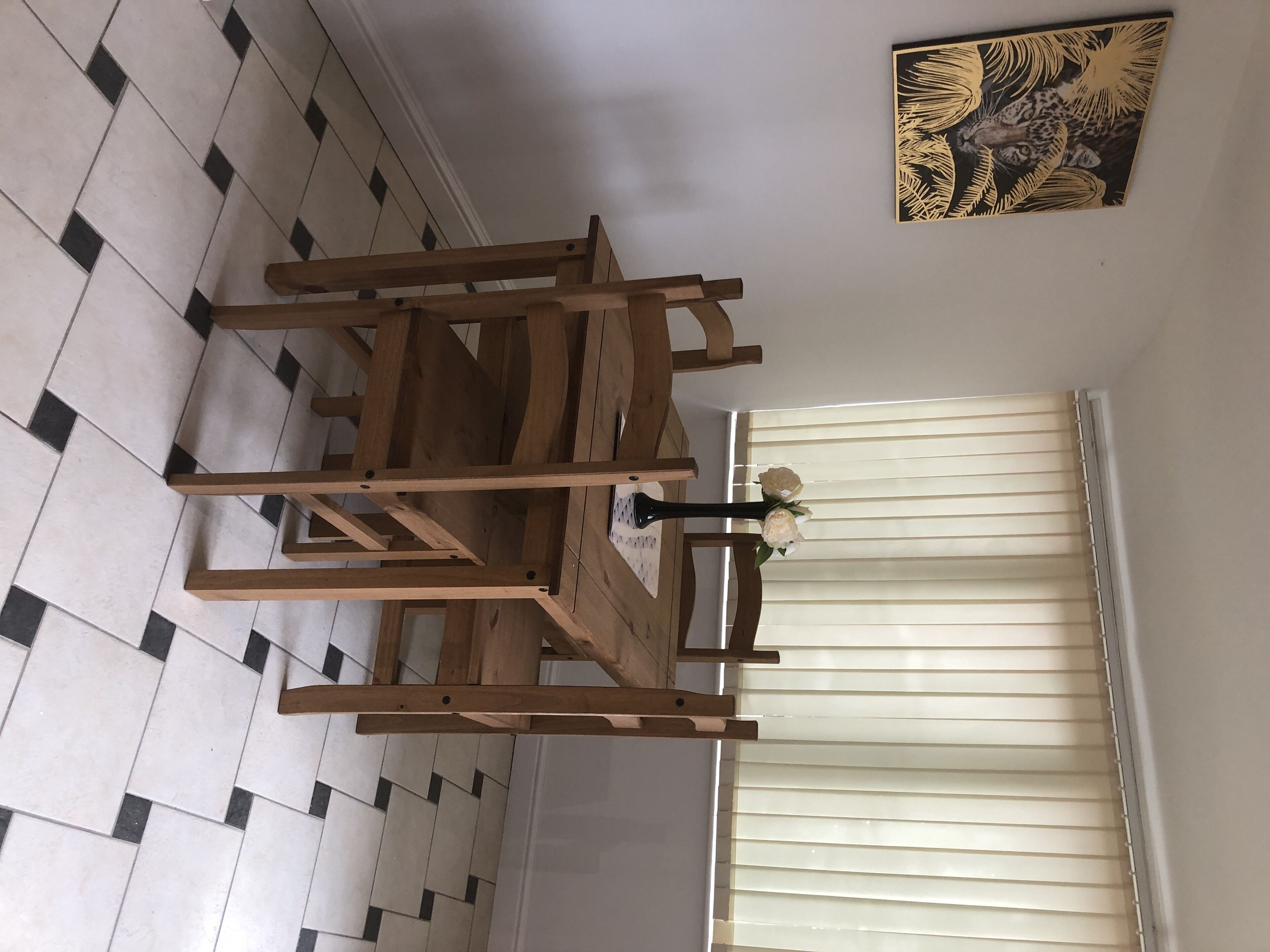 Ein Essbereich mit Holztisch und Stühlen, einer Blumenvase und einem Bild an der Wand.