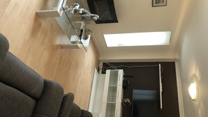 Uma sala de estar moderna com um sofá cinzento, um armário branco e uma cadeira preta.