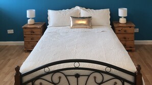 Quarto com cama, duas mesas de cabeceira e luminária no teto.