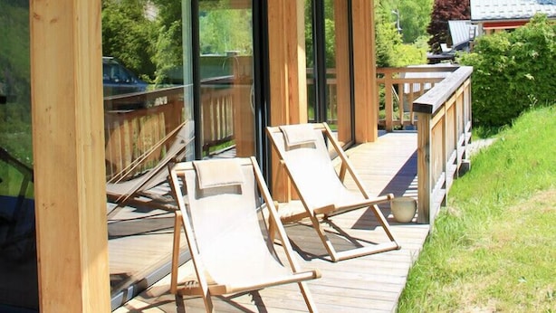 A wooden deck with two lounge chairs, large glass doors, and a view of a mountainous landscape. - Modern Chalet With Garden Chamonix (Chamonix-Mont-Blanc)
