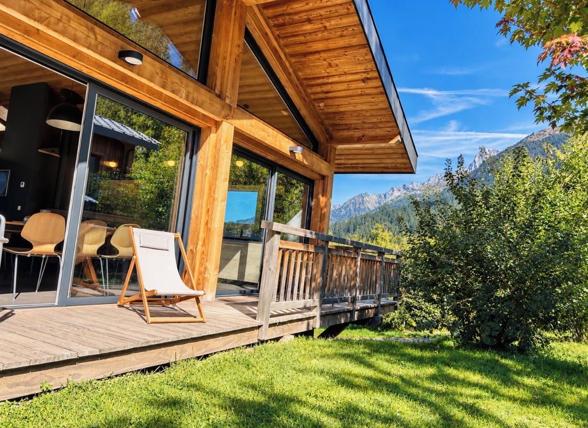 A wooden deck with outdoor seating, overlooking a mountainous landscape.