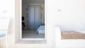 Een kamer met een bed, een stoel en een deur naar een andere kamer.
