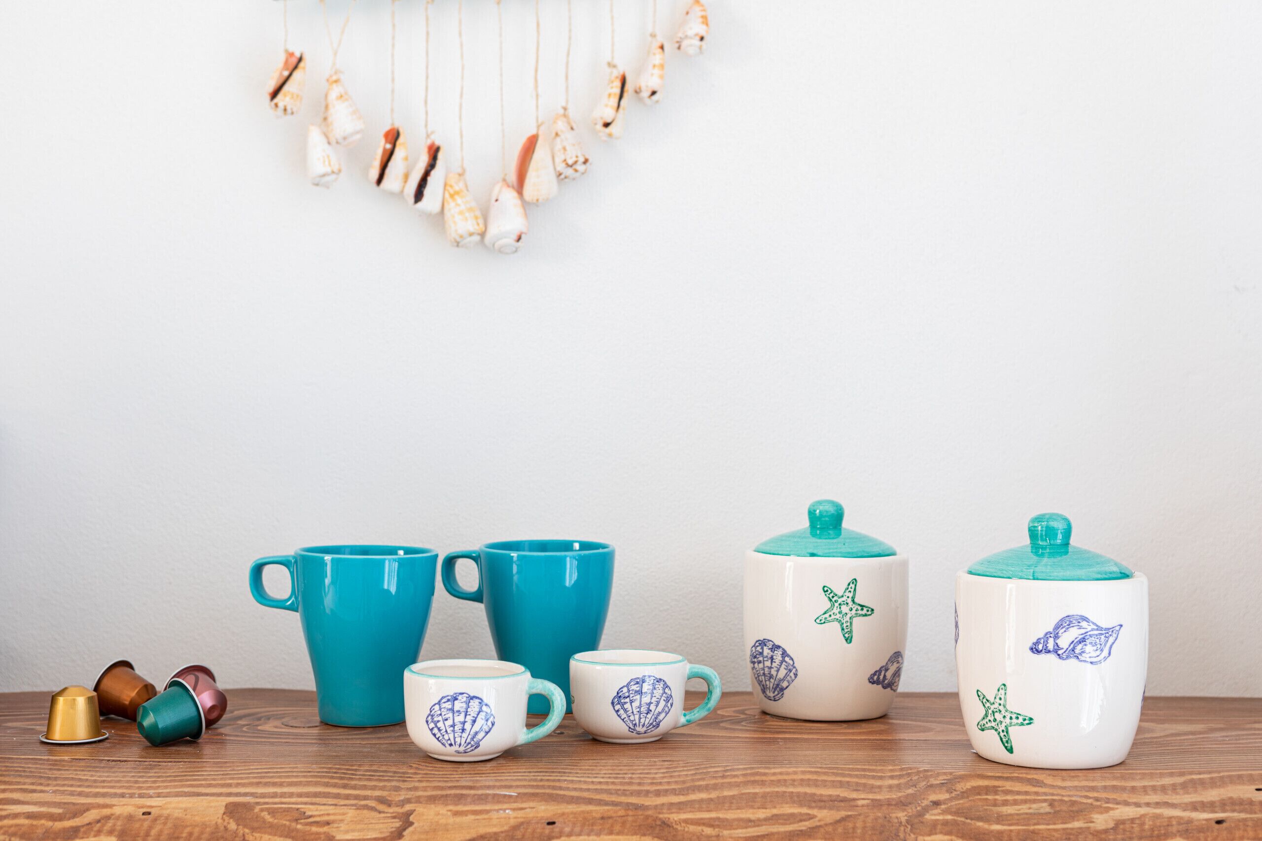 A wooden table with a set of ceramic mugs and a teapot, some with starfish designs.