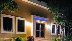 Um edifício moderno com entrada bem iluminada, caminho de pedra e arbustos bem aparados.