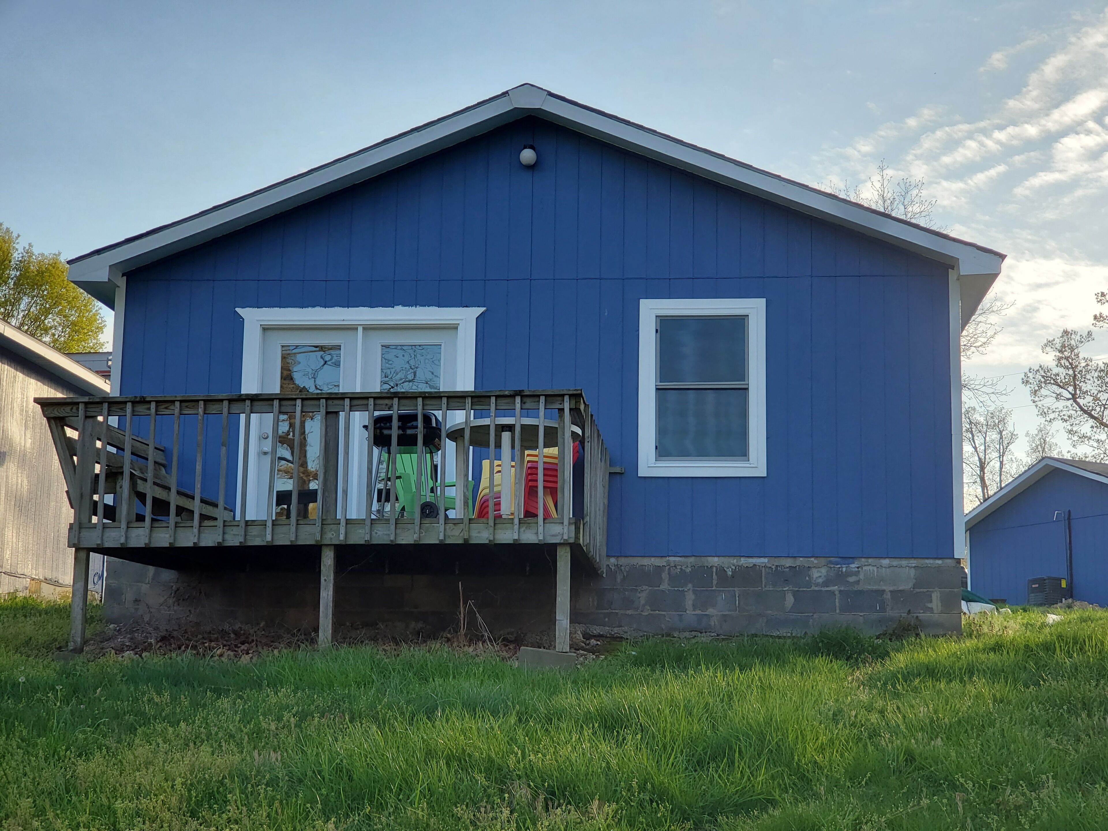 A blue house with a wooden deck and a window.