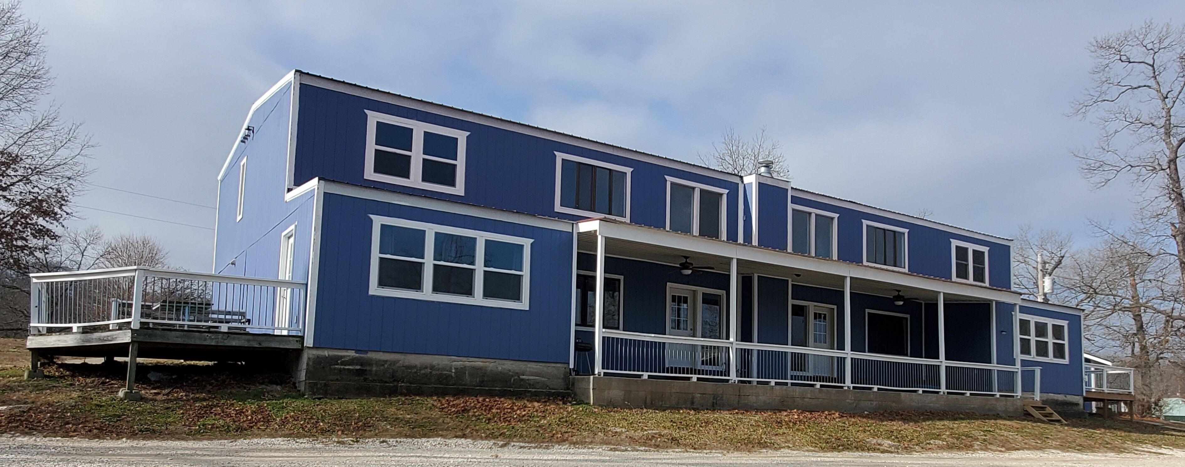 A two-story blue house with a balcony and a covered porch.