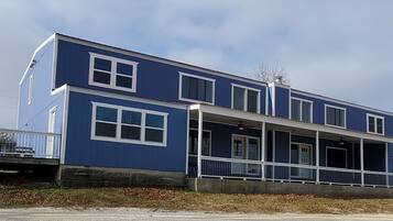 A two-story blue house with a balcony and a covered porch.
