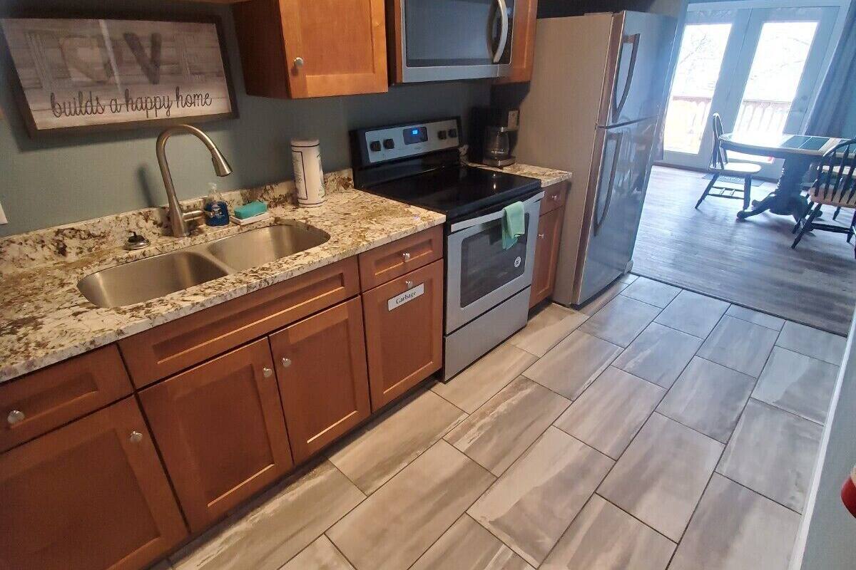 Una cocina con armarios de madera, encimera de granito, electrodomésticos de acero inoxidable y vistas al comedor.
