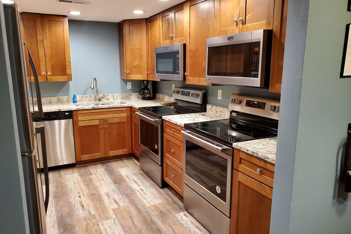 Una cocina con armarios de madera, electrodomésticos de acero inoxidable y encimera de granito.