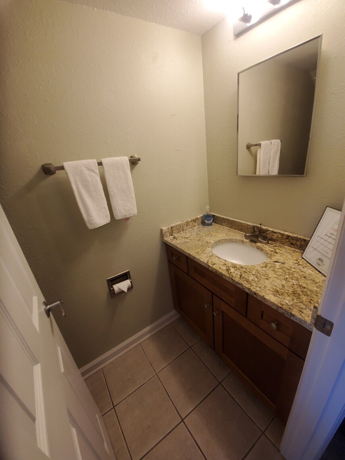 Un bagno con lavandino, specchio, portasciugamani e dispenser di carta igienica.