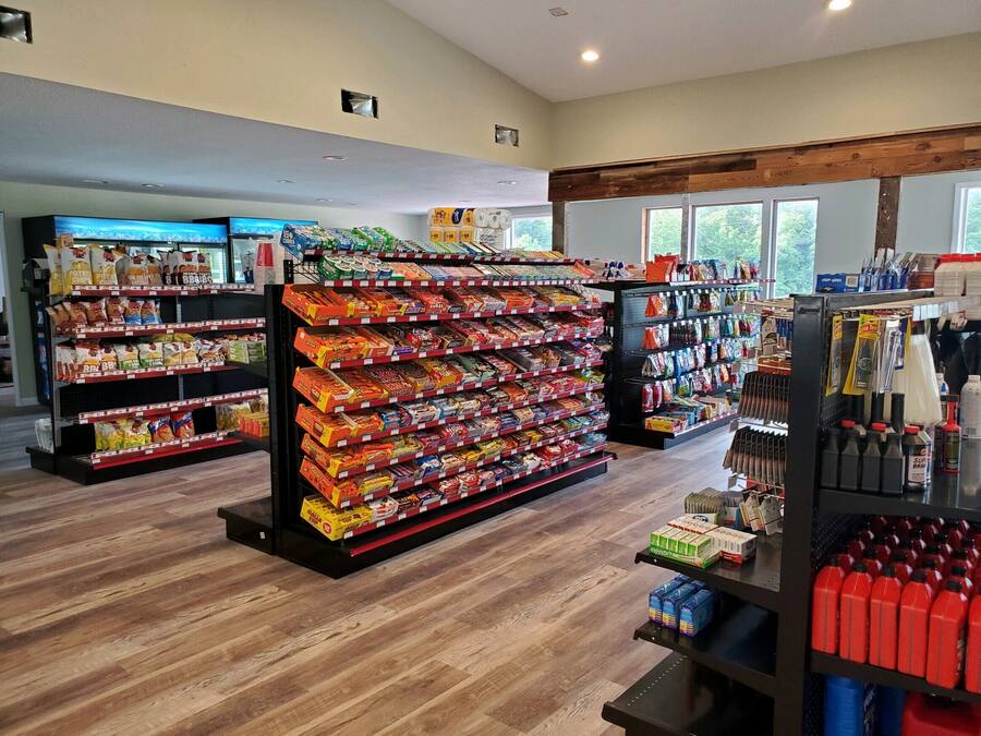 Interior de una tienda de comestibles con estantes llenos de productos y bebidas.