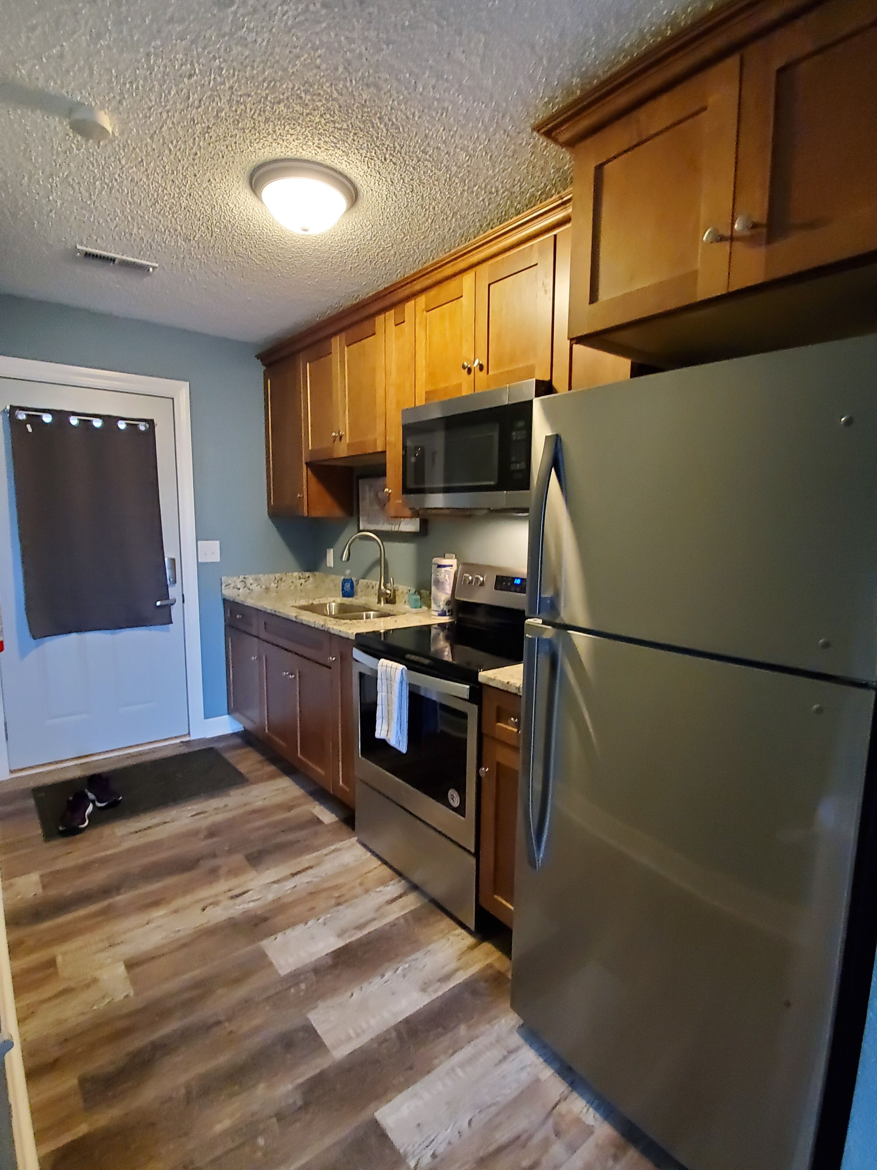 A kitchen with wooden cabinets, stainless steel appliances, and a herringbone wood floor.
