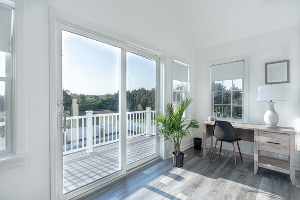 A spacious room with a large sliding glass door leading to a balcony, a wooden desk with a chair, and a potted plant. - 11-Bedroom Mansion with a Seasonal Outdoor Pool open now plus 10.5 bathrooms (Eastport)