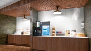 A reception area with a wooden counter, a beverage dispenser, and a coffee machine. - Fairfield Inn & Suites by Marriott Somerset (Somerset)