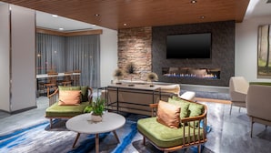 A modern living room with a stone accent wall, a flat-screen TV, a fireplace, and a blue patterned rug. - Fairfield Inn & Suites by Marriott Somerset (Somerset)